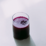 feri0242_a_clear_glass_of_rich_golden_Purple_juice_placed_on__ced1ee34-415c-475b-a144-f78beb5186b3_0